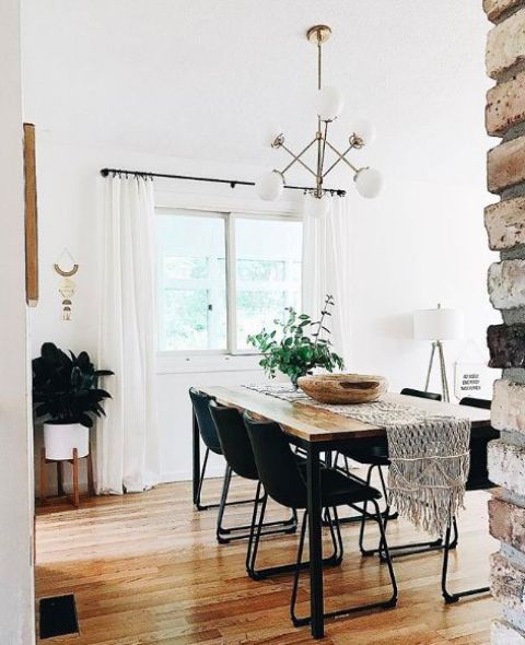a-modern-boho dining room with black chairs a sleek wooden table a macrame table runner and greenery
