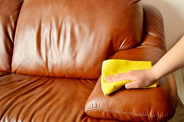 a man cleaning brown sofa
