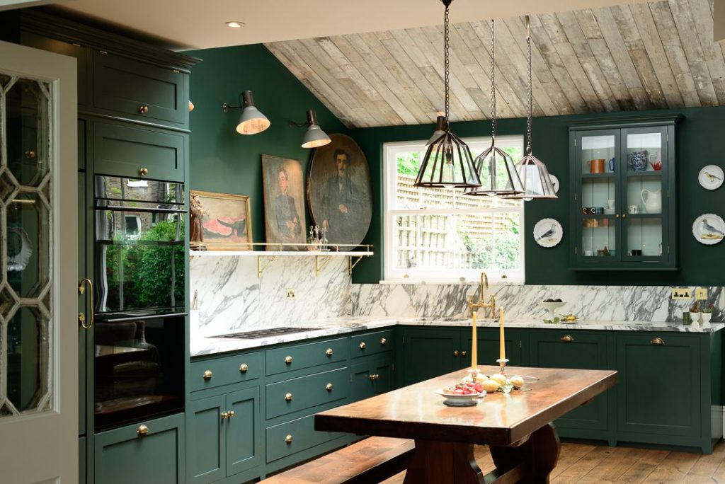 Earthy kitchen with green cabinets and a wooden table