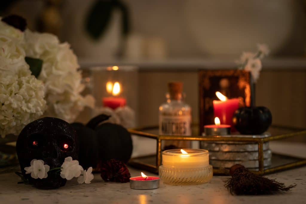 A spooky and witchy candle decor featuring a table adorned with candles and flowers