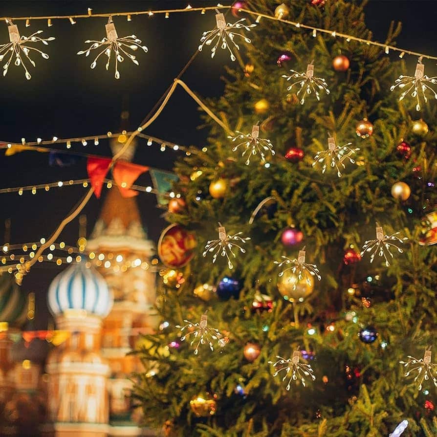 A beautifully decorated Christmas tree with lights and ornaments, set against the backdrop of the Kremlin, enhanced by Starburst Firework String Lights.