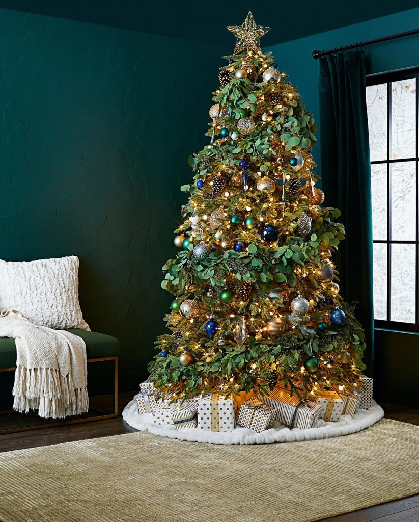 A beautifully decorated Christmas tree in a room with a green wall, illuminated by string lights