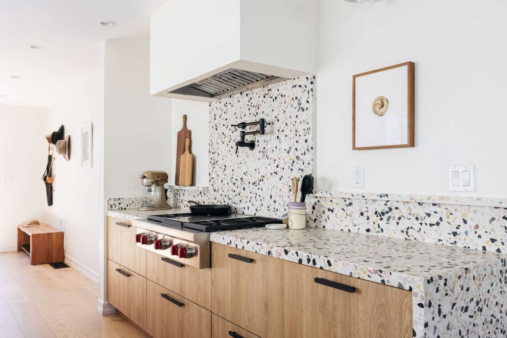 A modern kitchen with a stove, sink, and countertops made of Terrazzo Tiles