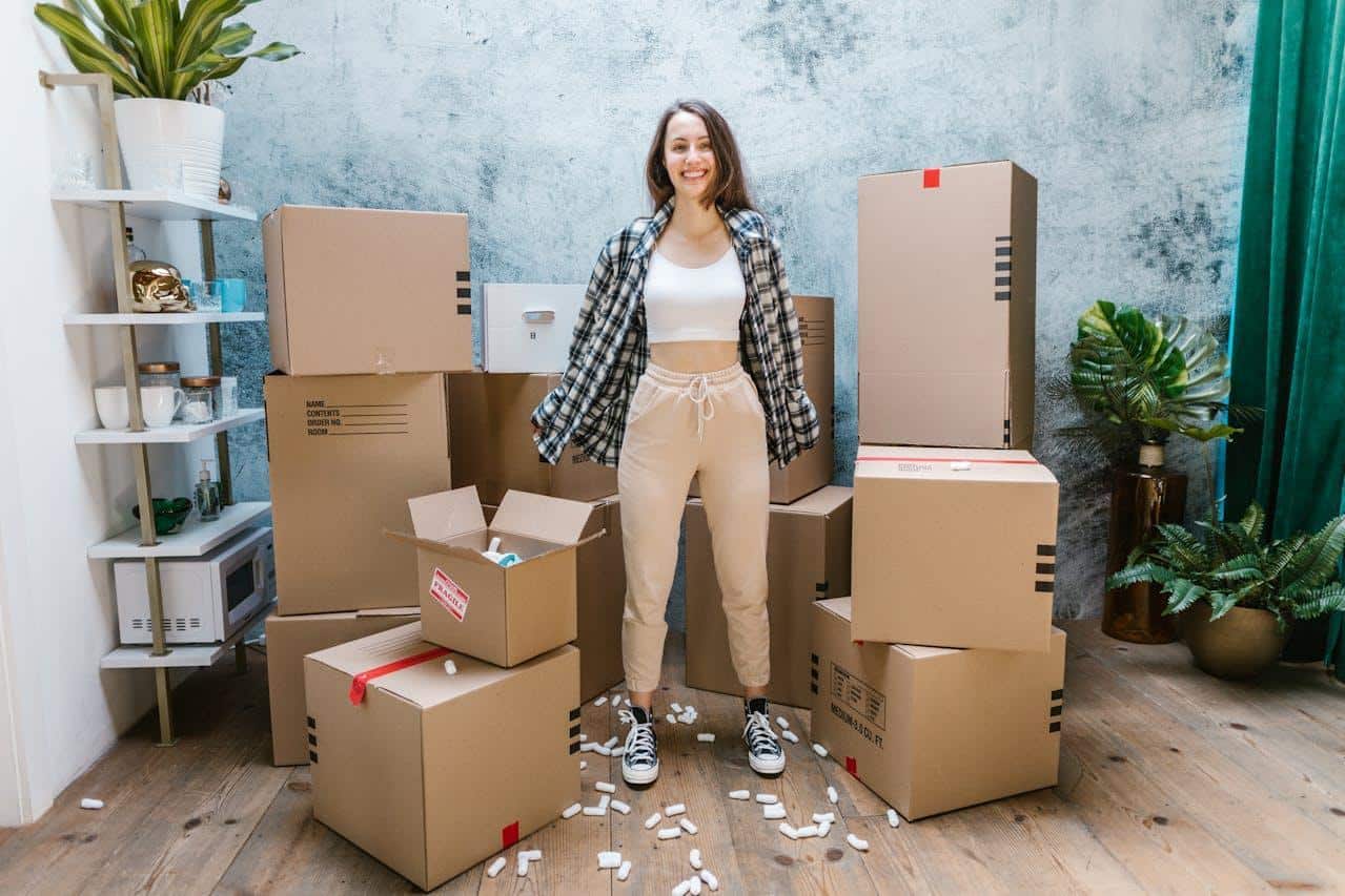 A woman in a white top crop standing in the middle of cardboard boxes.